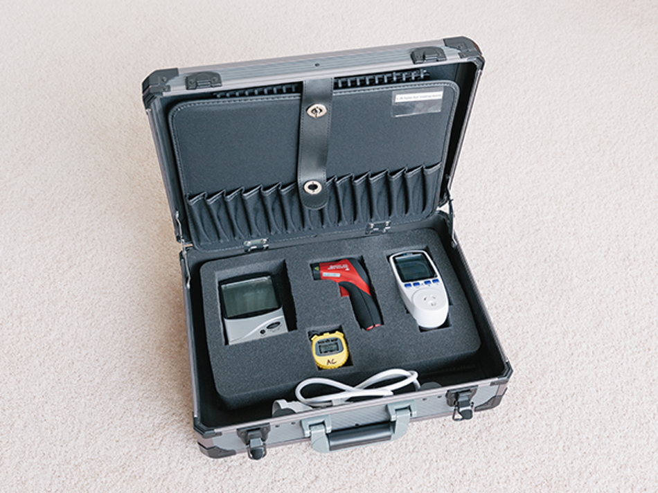 An open carrying case holding home energy assessment tools, including a thermal gun, power meter, and hygrometer.