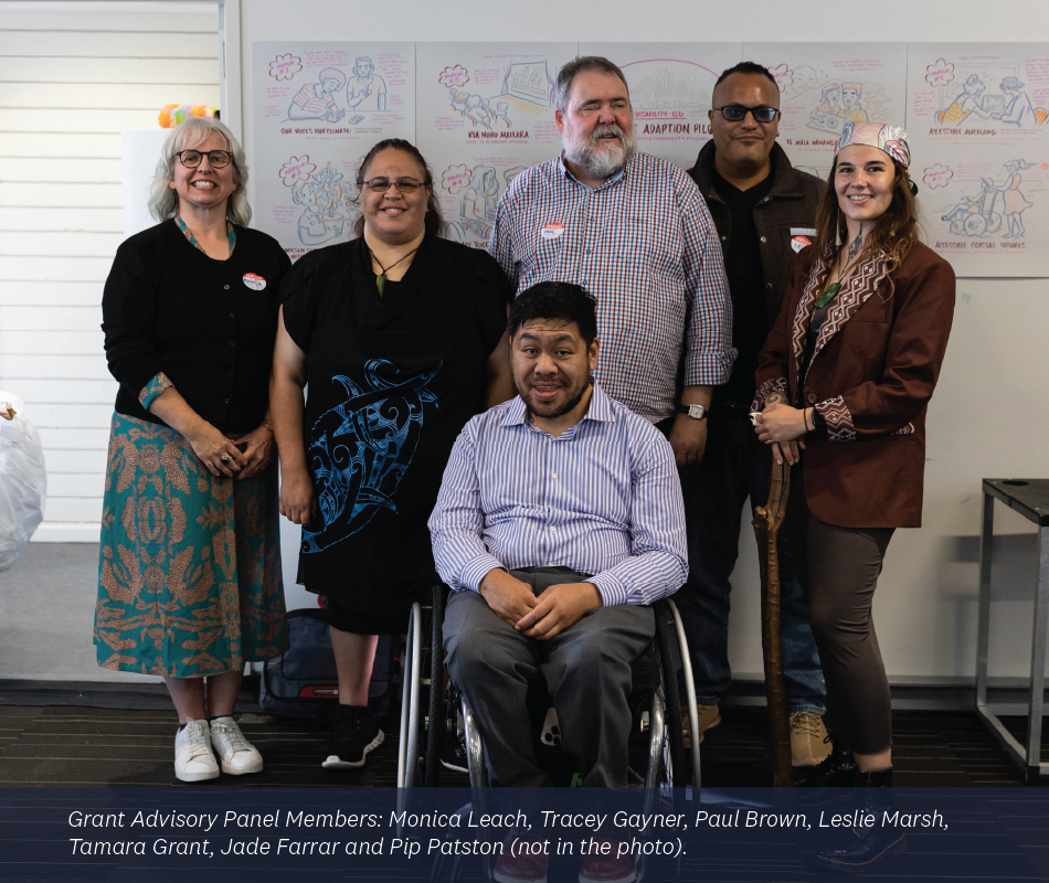 A Group Portrait Of Six People Posing Indoors. In The Center Foreground, A Man In A Striped Shirt Sits In A Wheelchair, Smiling.